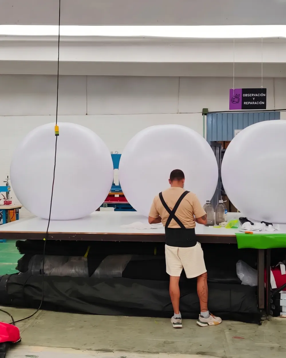 Trabajador en el taller, frente a una mesa con pelotas inflables gigantes